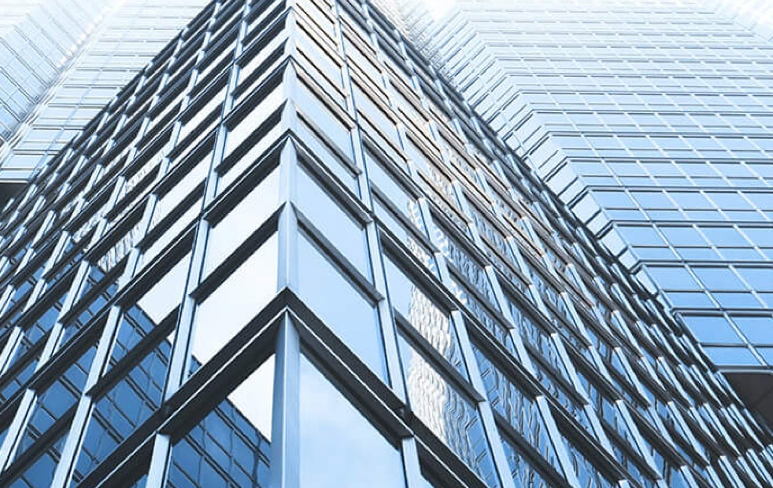 Grattacielo moderno con facciata di vetro riflettente e cielo azzurro sullo sfondo.