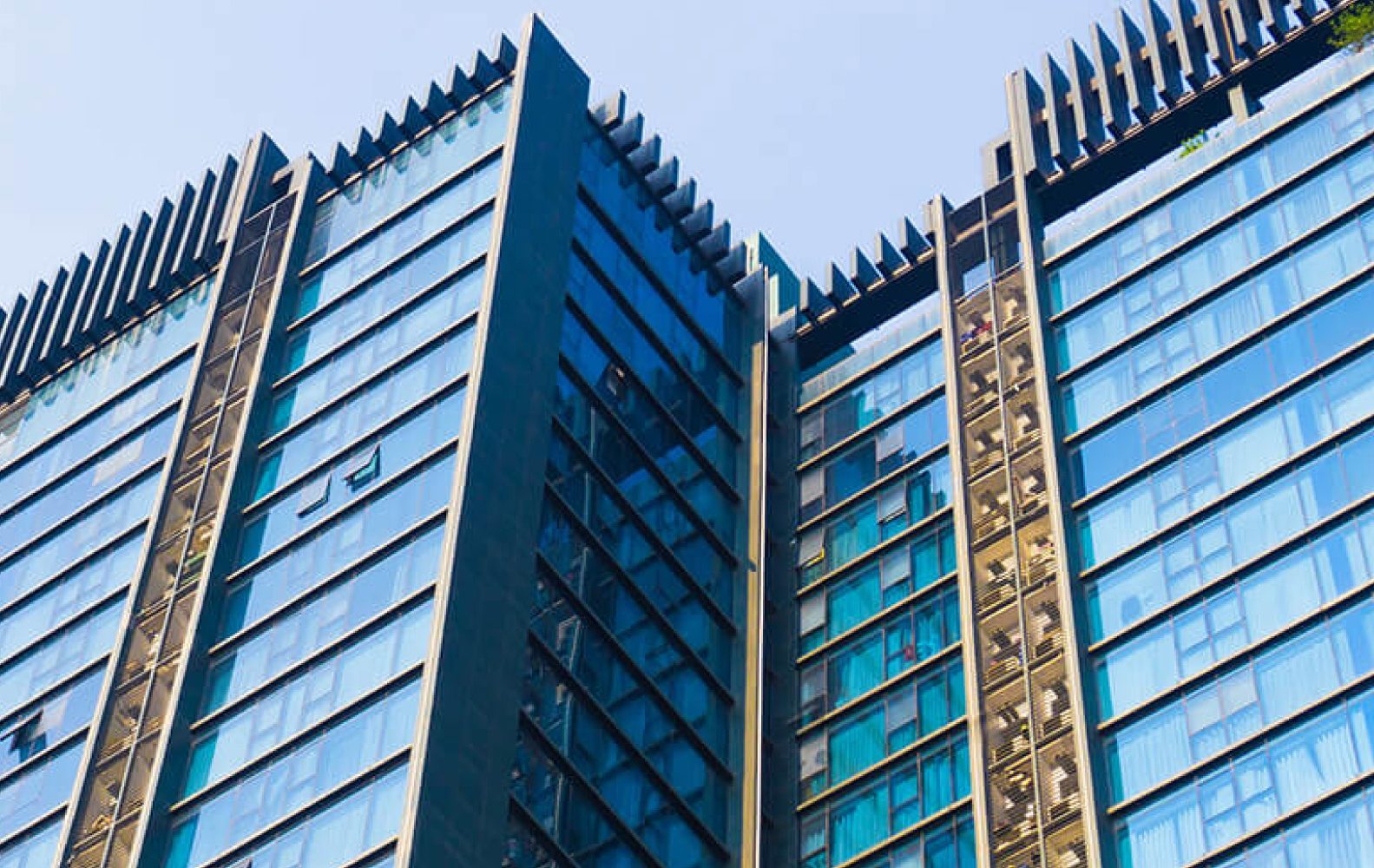 Grattacielo moderno con vetri riflettenti sotto un cielo azzurro, architettura urbana contemporanea.