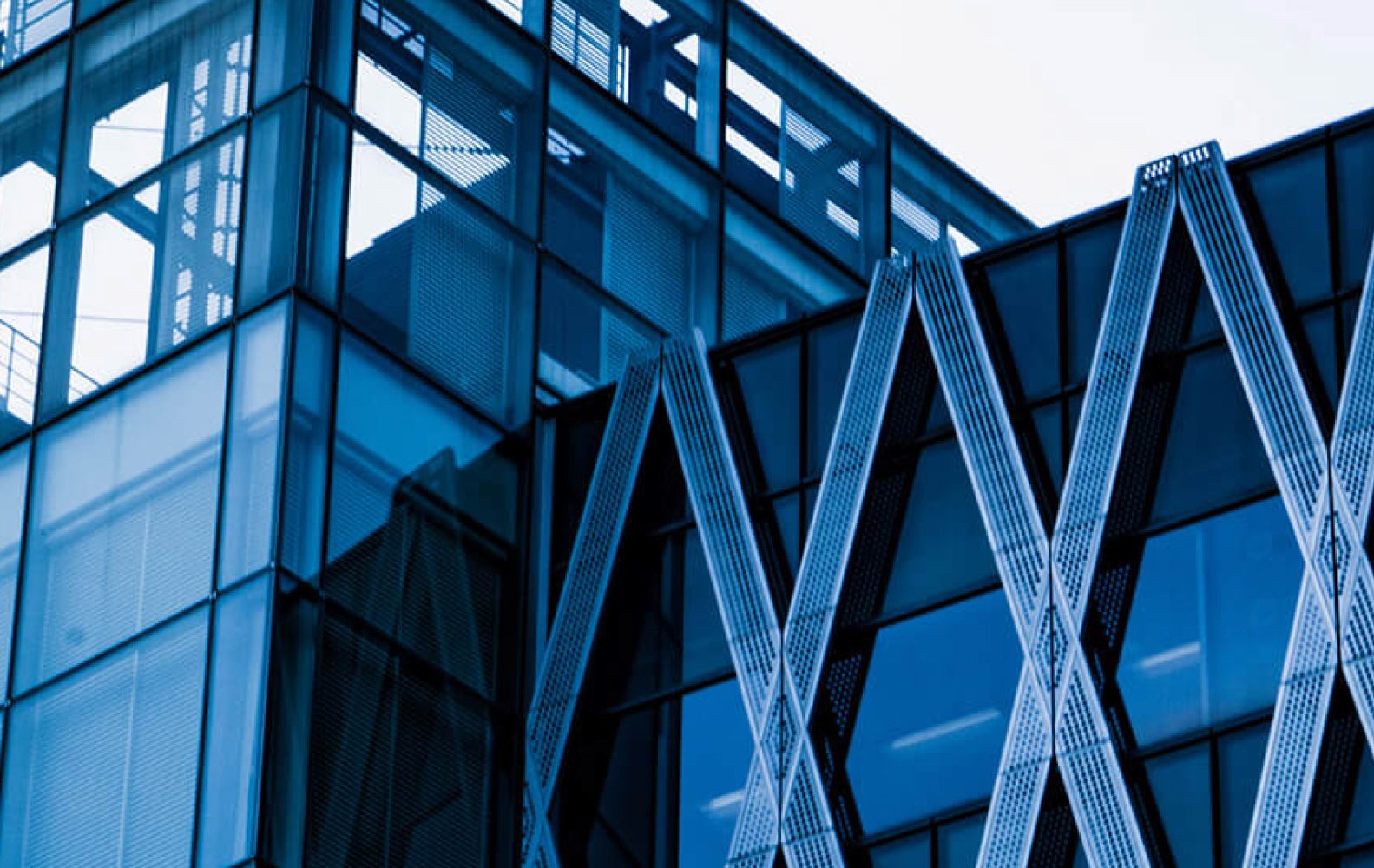 Moderno edificio in vetro con struttura a griglia metallica, dettagli architettonici geometrici e design futuristico.