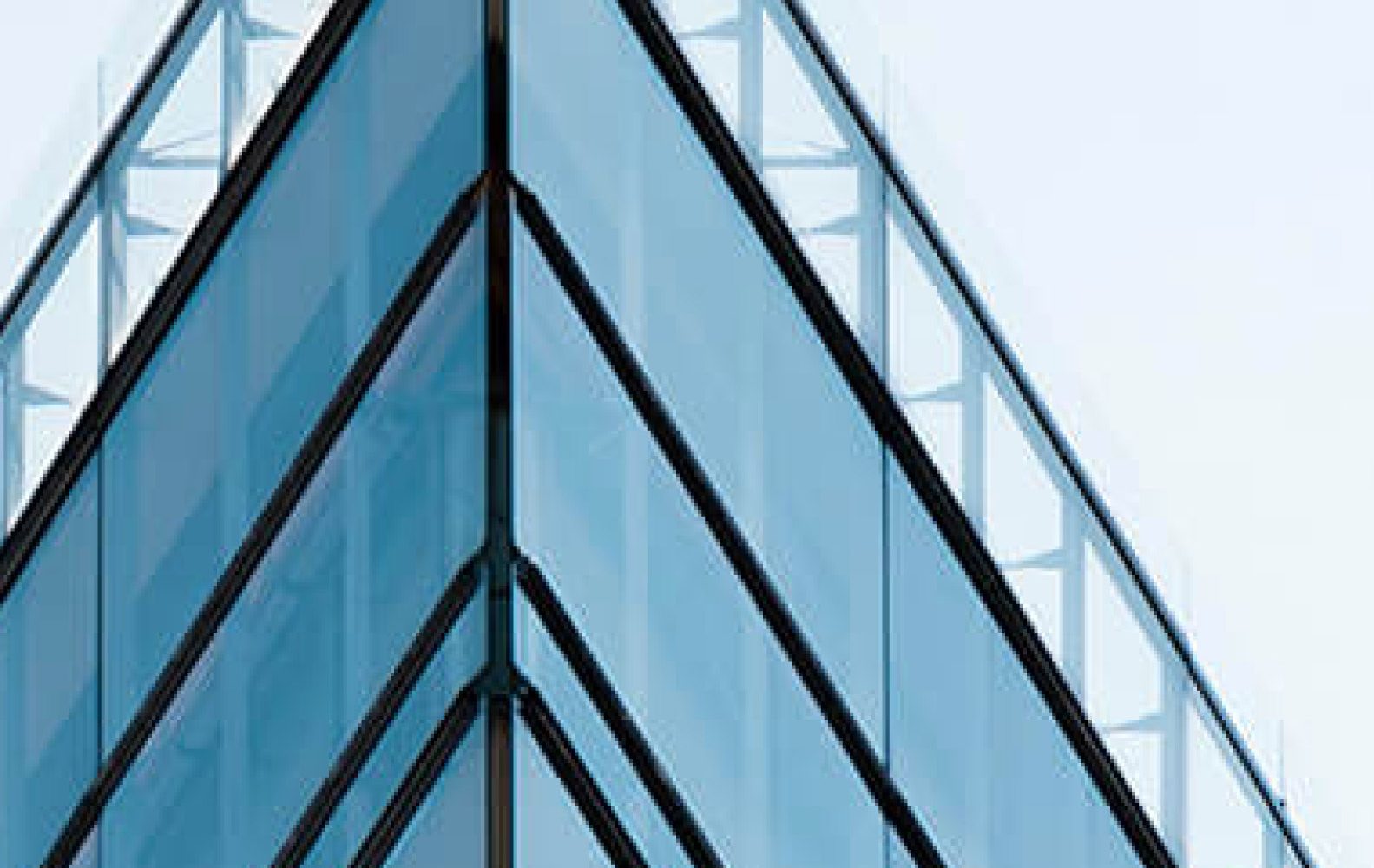 Angolo di un moderno edificio in vetro con dettagli architettonici eleganti e riflessi blu.