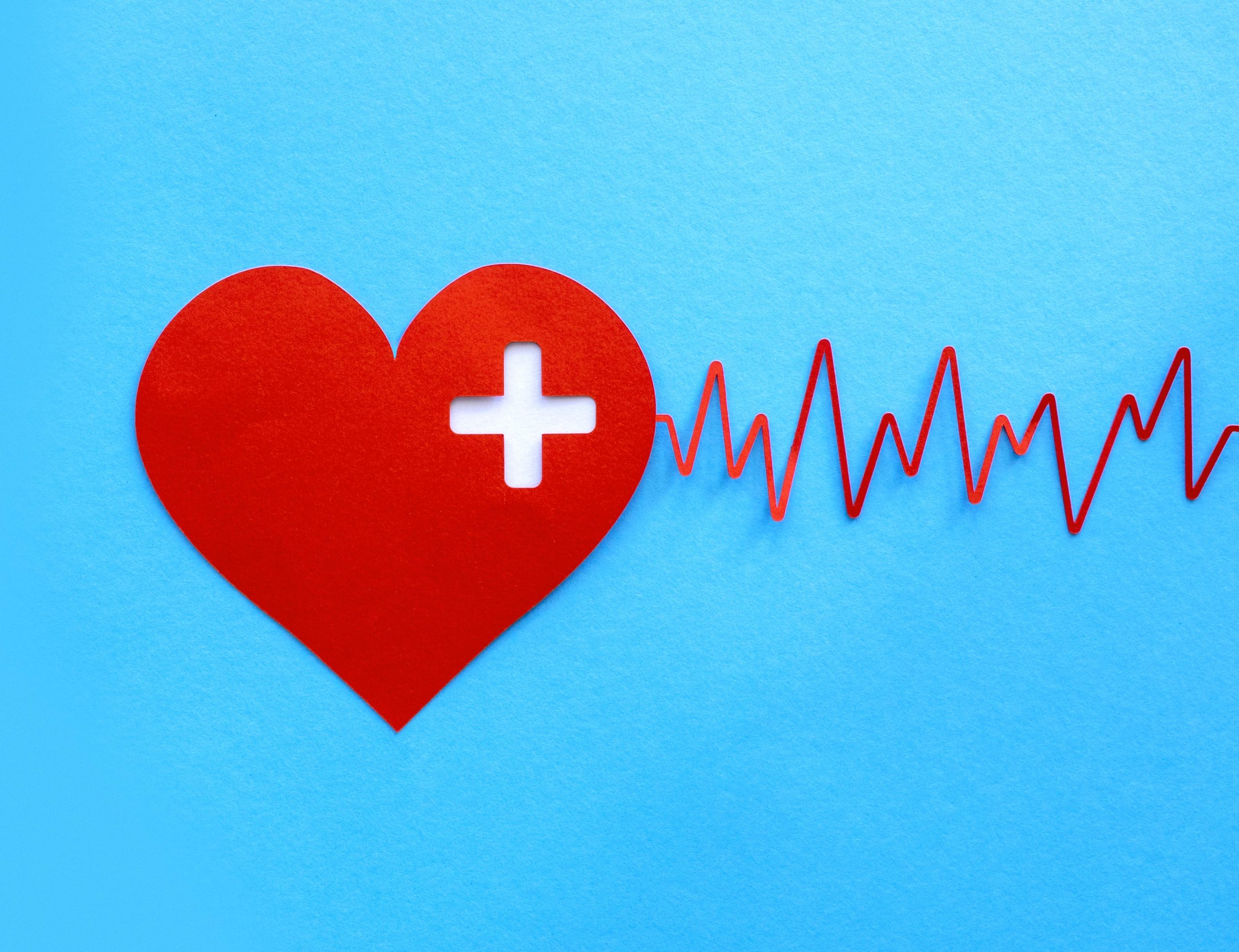 Cuore rosso con simbolo medico e battito cardiaco su sfondo blu, rappresenta la salute e il benessere.
